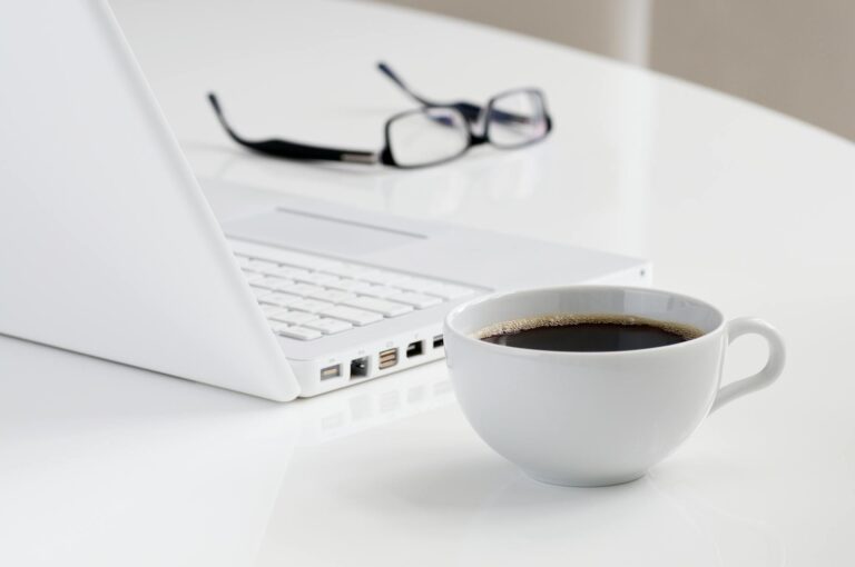 Dienstag Sprüche – Minimalistischer Arbeitsplatz mit Laptop, schwarzem Kaffee und Brille