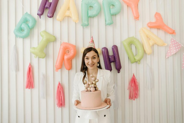 Die besten Geburtstagsgrüße: Lustig, kostenlos & für WhatsApp Die besten Geburtstagsgrüße – Frau feiert mit bunten Ballons und Torte