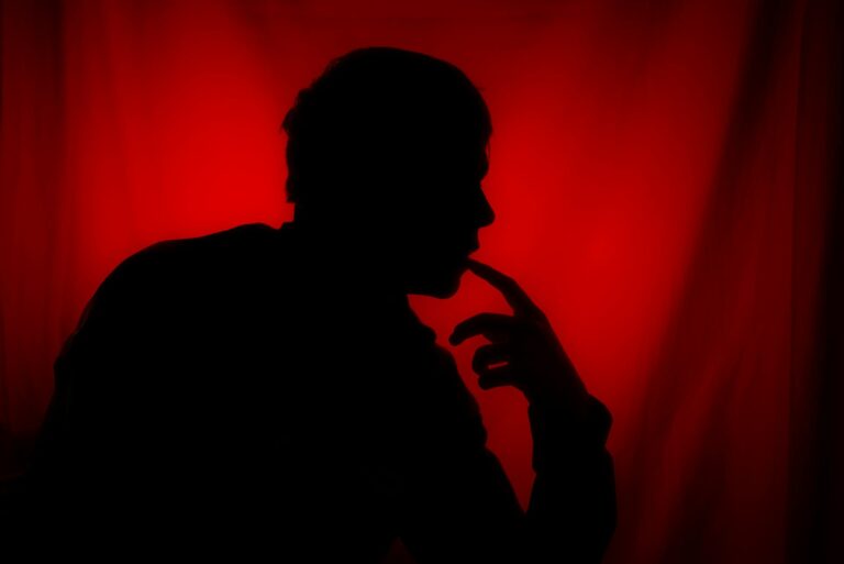 Harte aber wahre Sprüche – Silhouette einer Person in Gedanken vor rotem Hintergrund
