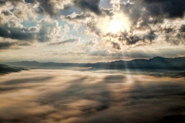 Hoffnung Sprüche – Sonne bricht durch die Wolken über einer Berglandschaft, Symbol für Hoffnung
