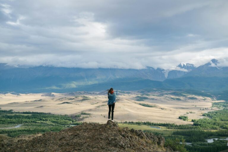 Lebensmotto Sprüche – Person auf einem Berggipfel mit Blick auf weite Bergketten