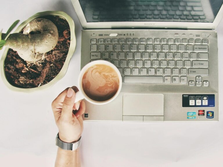 Montag Sprüche: 350 Sprüche für Montag zum Wochenstart Montag Sprüche – gemütlicher Arbeitsplatz mit Laptop, Kaffeetasse und Pflanze am Morgen
