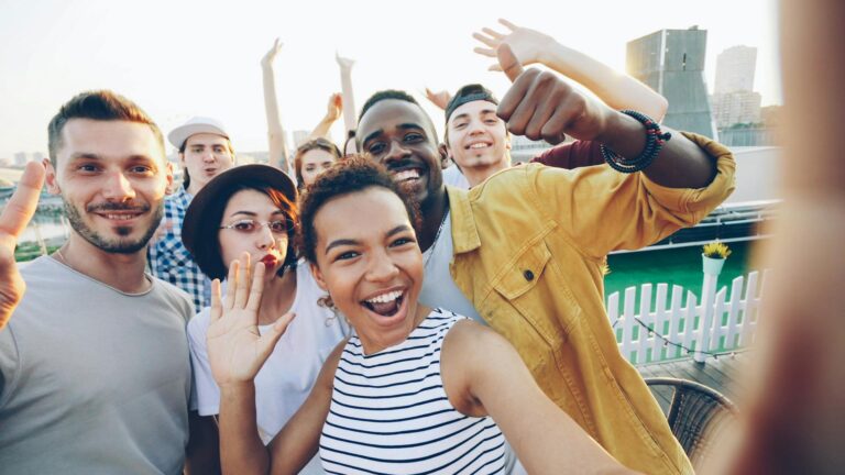 Rizz Sprüche – Junge Leute lachen bei einer Rooftop-Party und genießen die Atmosphäre