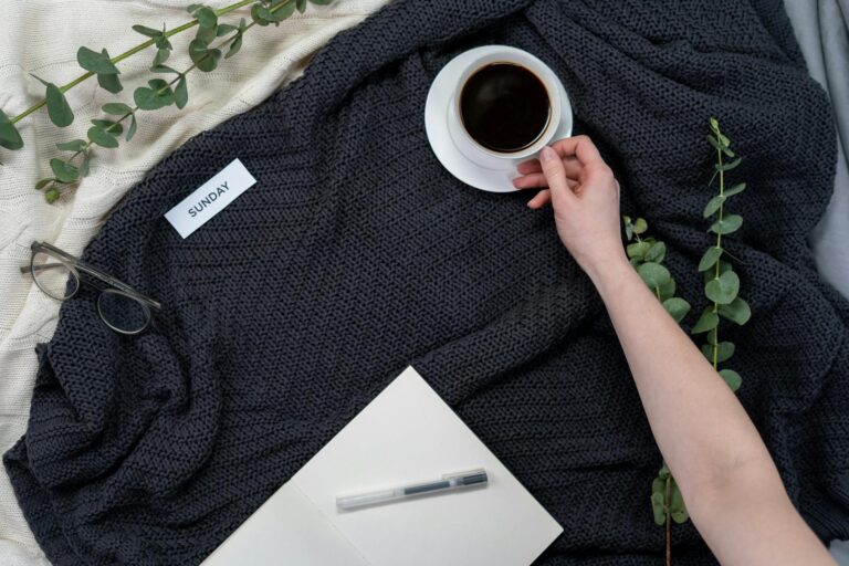 Schönen Sonntag, gemütliche Morgenszene mit Kaffee, Notizbuch und Brille auf einer Decke